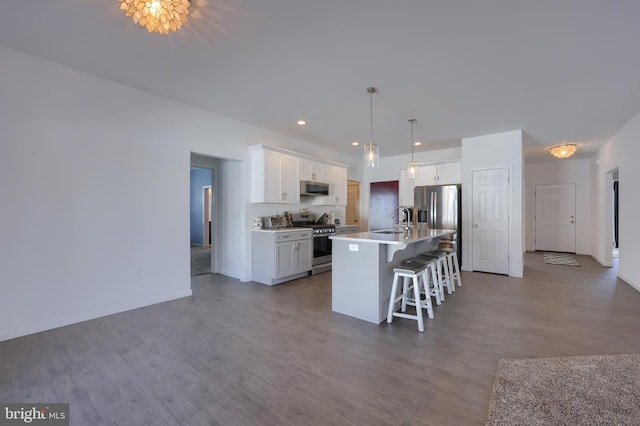 kitchen with appliances with stainless steel finishes, a center island with sink, white cabinetry, and hardwood / wood-style floors