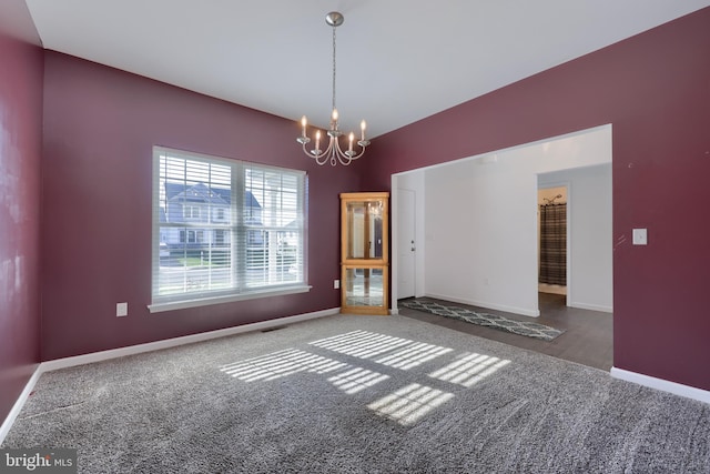 carpeted empty room featuring a chandelier