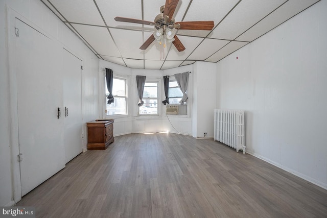 unfurnished room with light wood-type flooring, radiator, cooling unit, and ceiling fan