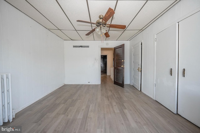 unfurnished bedroom with ceiling fan, light wood-type flooring, and radiator heating unit