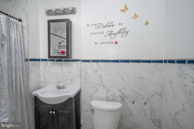 bathroom featuring curtained shower, vanity, tile walls, and toilet