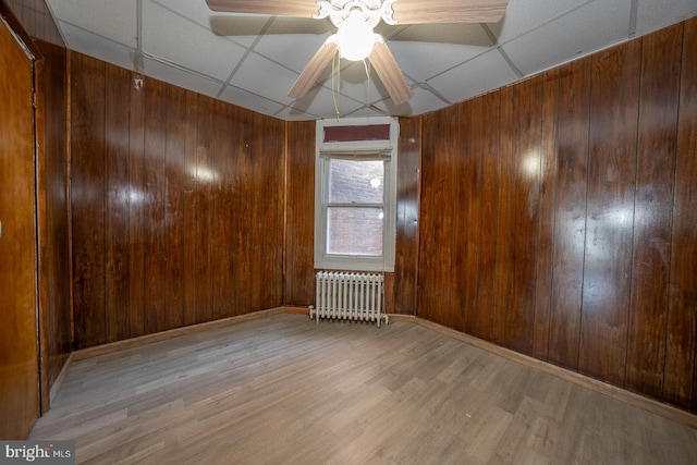 unfurnished room featuring radiator, a paneled ceiling, ceiling fan, and light hardwood / wood-style floors