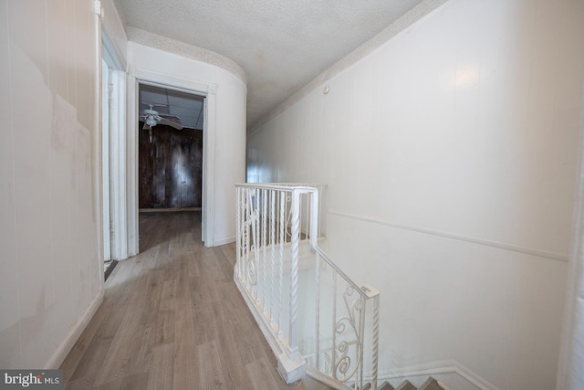 hallway with a textured ceiling and light hardwood / wood-style floors