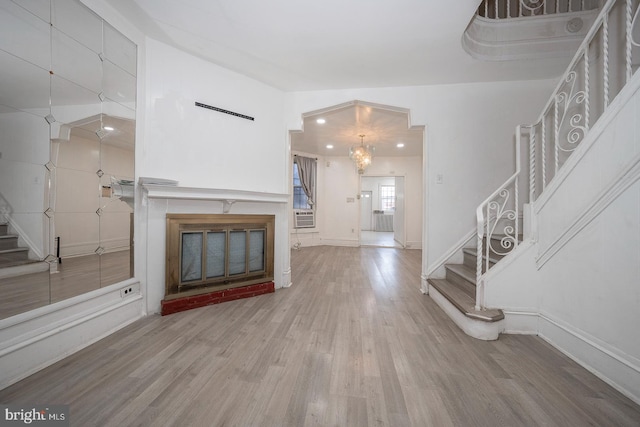 unfurnished living room with wood-type flooring and a chandelier