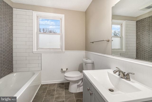 full bathroom featuring tiled shower / bath, vanity, and toilet