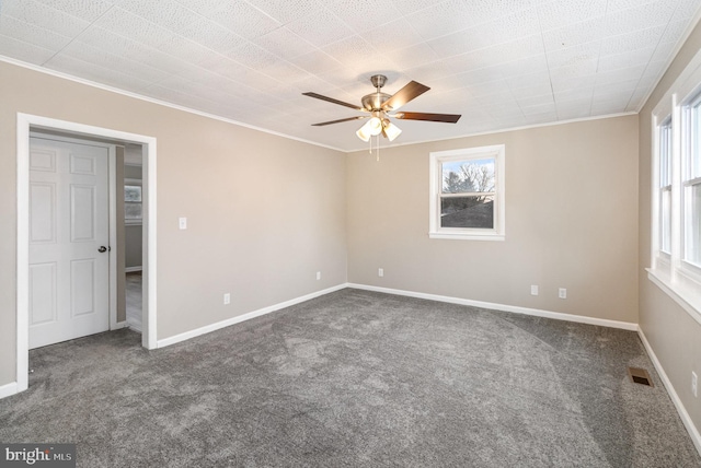 spare room featuring dark colored carpet, ceiling fan, and ornamental molding