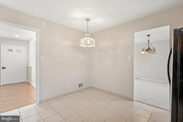 unfurnished room with light tile patterned flooring and a chandelier