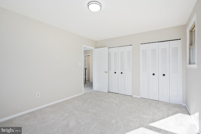 unfurnished bedroom featuring light colored carpet and two closets