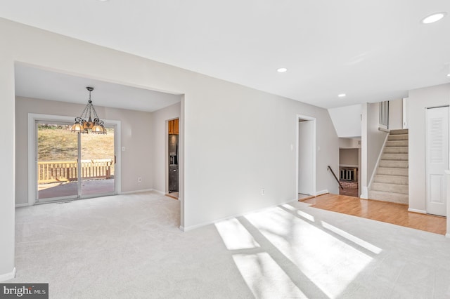 unfurnished living room with lofted ceiling, light carpet, and an inviting chandelier