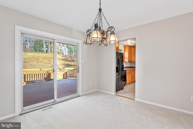 unfurnished dining area featuring a chandelier and light colored carpet