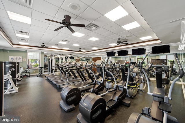 gym with a paneled ceiling, a raised ceiling, ceiling fan, and crown molding