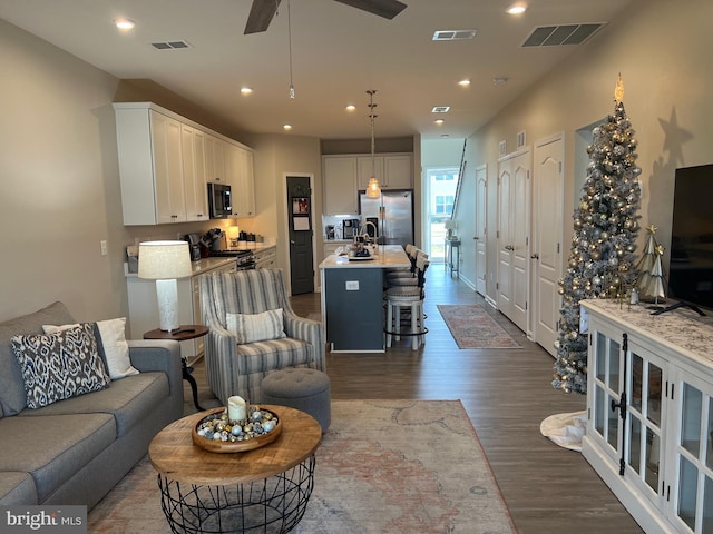 living room featuring ceiling fan and dark hardwood / wood-style flooring