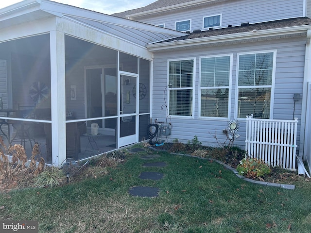 view of home's exterior with a sunroom and a yard