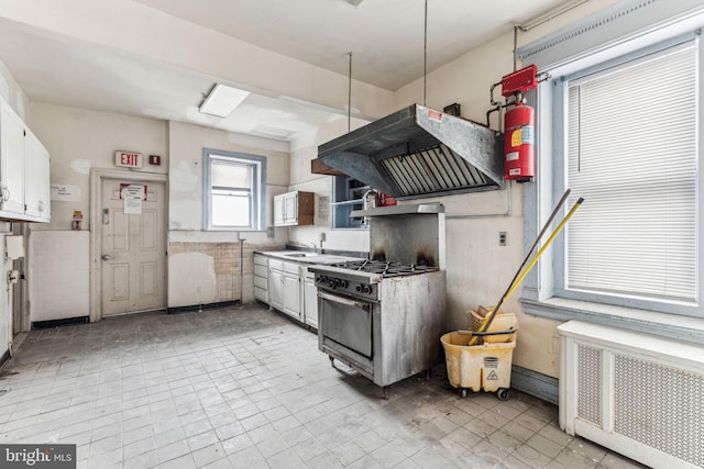 kitchen with white cabinetry, radiator heating unit, extractor fan, and gas stove