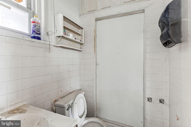 bathroom featuring toilet and tile walls