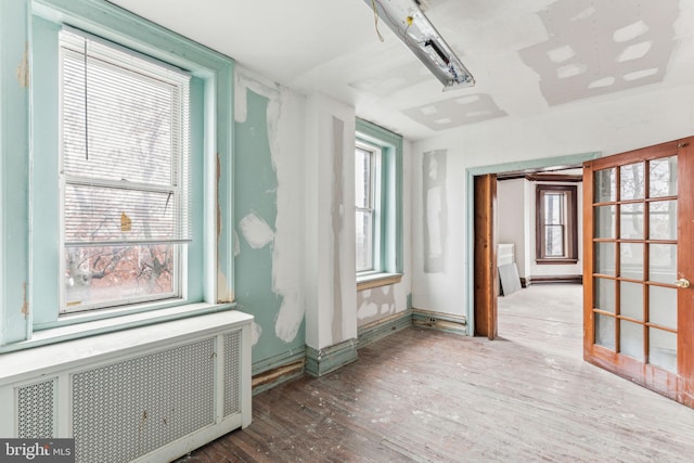 empty room featuring hardwood / wood-style flooring, plenty of natural light, and radiator heating unit