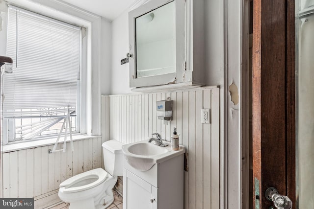 bathroom featuring tile patterned floors, wood walls, vanity, and toilet