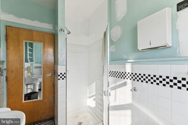 bathroom featuring a shower with shower door and tile walls