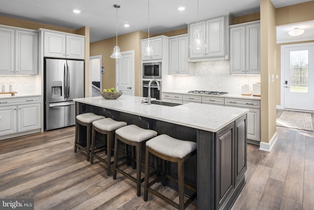 kitchen featuring dark hardwood / wood-style floors, sink, stainless steel appliances, and a kitchen island with sink