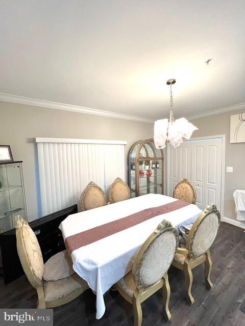 dining area with dark hardwood / wood-style flooring, crown molding, and a notable chandelier