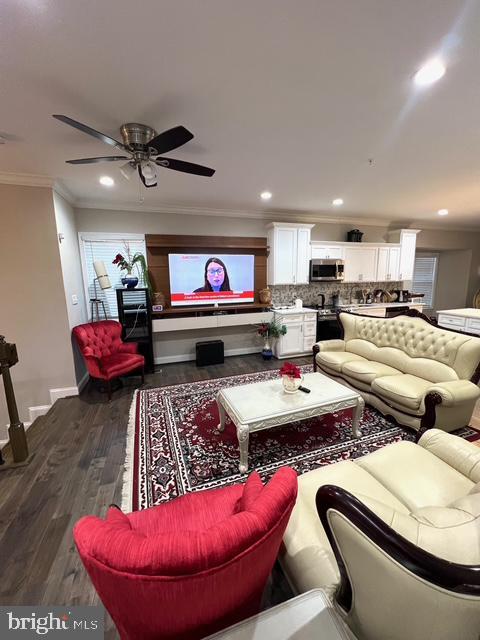 living room featuring ceiling fan, crown molding, and dark wood-type flooring