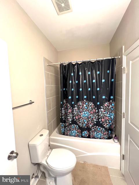 bathroom featuring shower / bath combo, toilet, and tile patterned floors