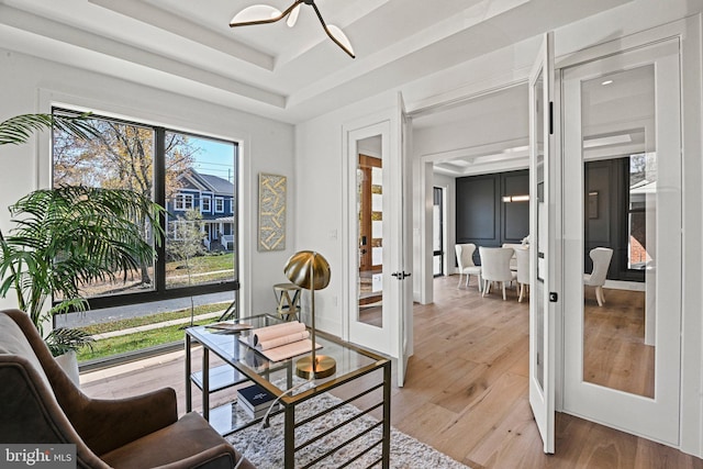 interior space with french doors, a raised ceiling, and hardwood / wood-style floors