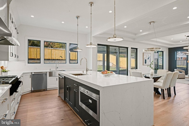 kitchen with white cabinetry, an island with sink, decorative light fixtures, and appliances with stainless steel finishes