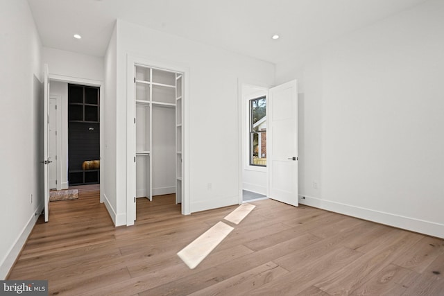 unfurnished bedroom with a closet, a walk in closet, and light hardwood / wood-style flooring