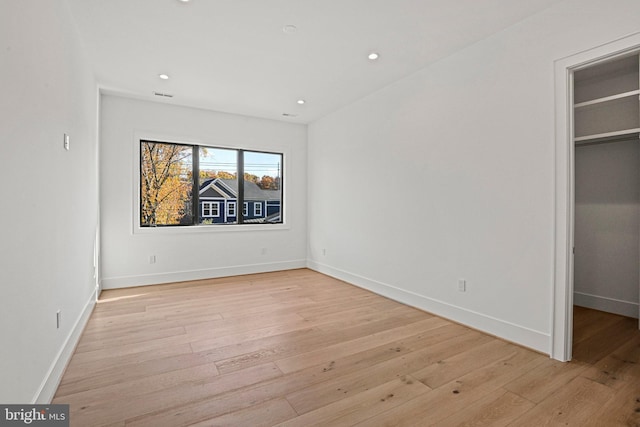 unfurnished bedroom featuring light hardwood / wood-style floors and a walk in closet