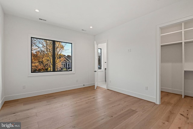 unfurnished bedroom featuring light hardwood / wood-style floors, a spacious closet, and a closet