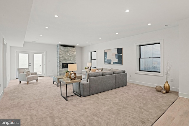 living room featuring light hardwood / wood-style floors, a stone fireplace, and french doors