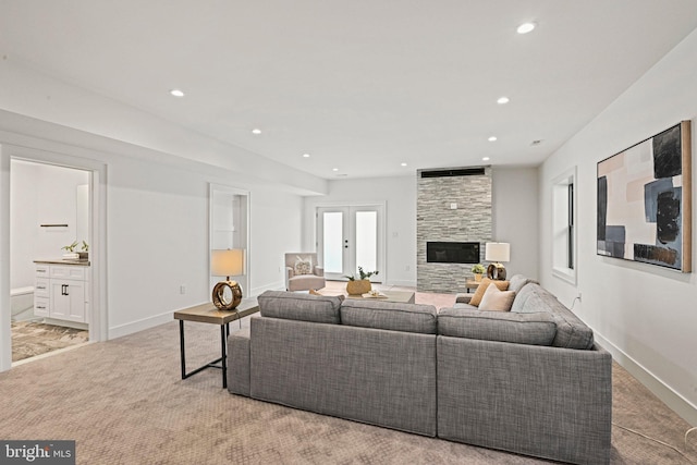 living room featuring french doors, light colored carpet, and a stone fireplace