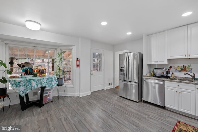 kitchen featuring white cabinets, sink, light hardwood / wood-style flooring, light stone counters, and stainless steel appliances