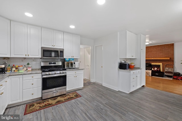 kitchen with light hardwood / wood-style flooring, white cabinets, and appliances with stainless steel finishes