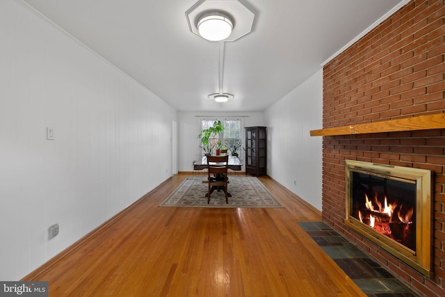 unfurnished dining area with a fireplace, ornamental molding, and hardwood / wood-style flooring