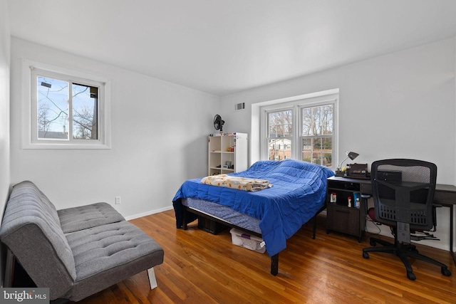 bedroom with dark hardwood / wood-style floors and multiple windows