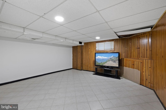 basement with a drop ceiling and wooden walls