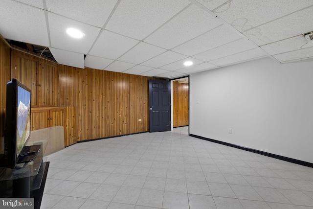 basement with a paneled ceiling and wood walls