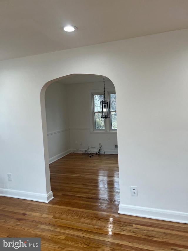 empty room with hardwood / wood-style floors and a chandelier