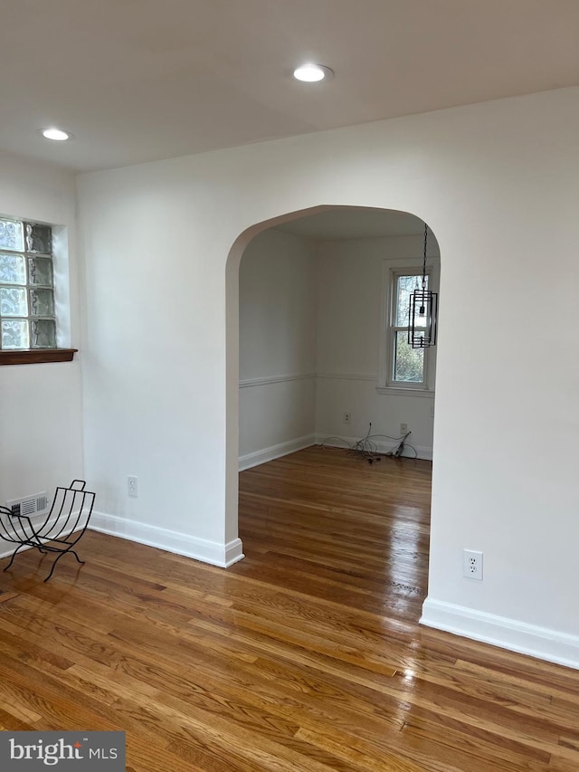 spare room with wood-type flooring and a chandelier