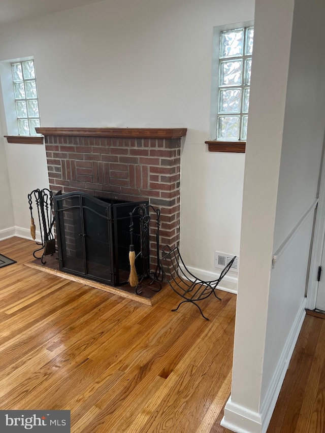 interior details featuring a brick fireplace and wood-type flooring