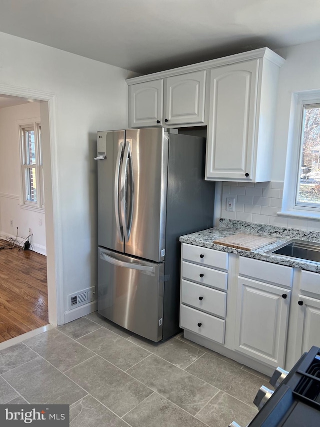 kitchen featuring white cabinetry, plenty of natural light, and stainless steel fridge