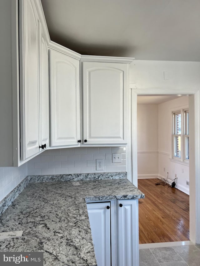 kitchen featuring light stone countertops, light tile patterned floors, decorative backsplash, and white cabinets