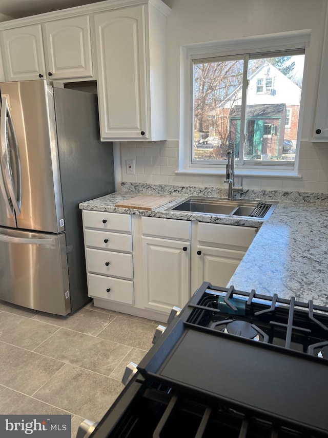 kitchen featuring white cabinetry, stainless steel fridge, sink, and decorative backsplash