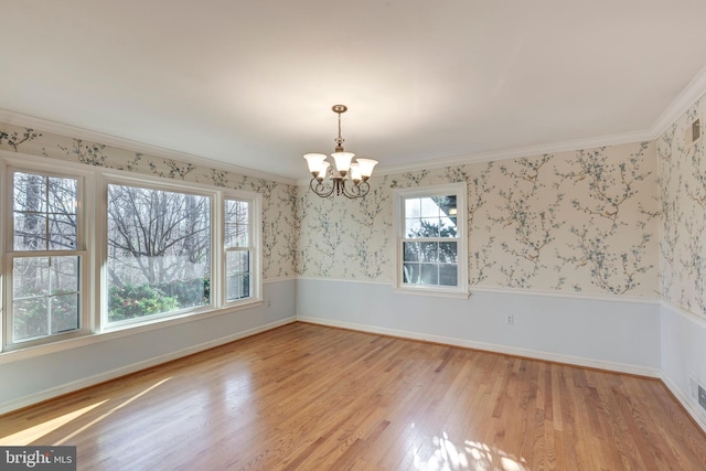 unfurnished dining area featuring crown molding, light hardwood / wood-style flooring, and an inviting chandelier