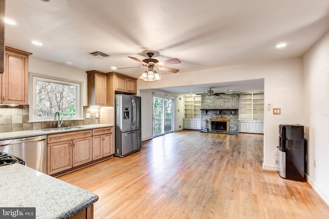 kitchen with sink, light hardwood / wood-style flooring, ceiling fan, appliances with stainless steel finishes, and tasteful backsplash