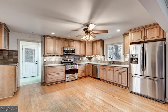 kitchen featuring ceiling fan, sink, stainless steel appliances, tasteful backsplash, and light hardwood / wood-style flooring