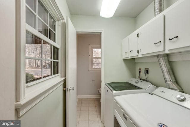 washroom with cabinets, washer and clothes dryer, a healthy amount of sunlight, and light tile patterned flooring