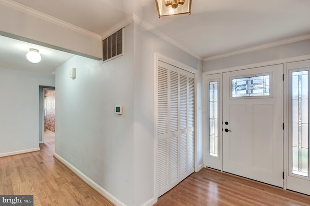 entrance foyer featuring light wood-type flooring, plenty of natural light, and ornamental molding